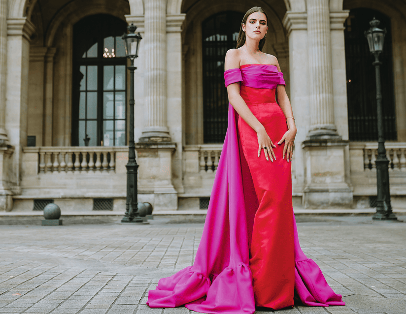 Duchesse satin gown in red and magenta with draped off shoulder details, with detachable silk gazar magenta cape by Mark Bumgarner.
